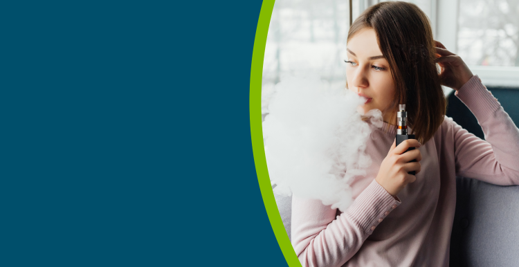 A young person vaping, whilst sat in a chair by a window