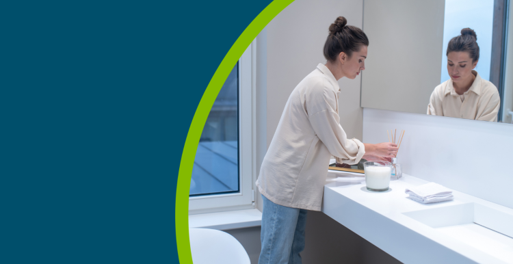 A young woman putting air freshener in the bathroom