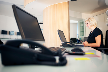 A receptionist sat behind a desk at a GP practice