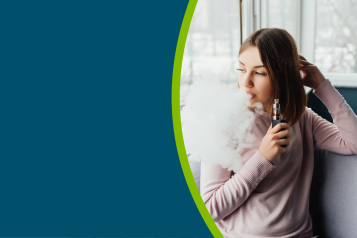 A young person vaping, whilst sat in a chair by a window