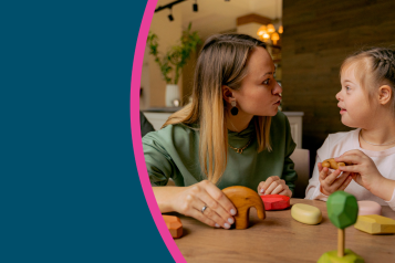 A child and adult sat a table playing a game.