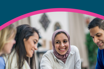 A mix of people sat at a table, smiling and discussing equality, diversity and inclusion.