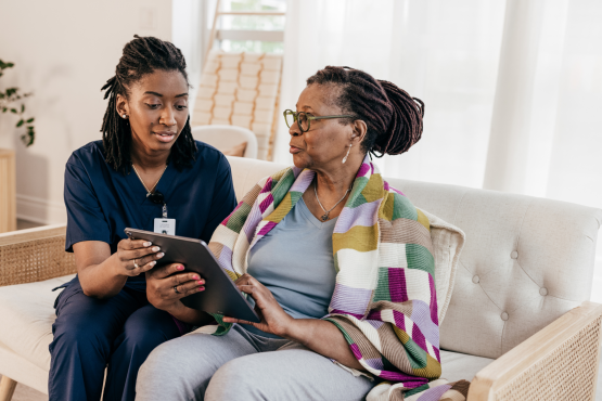 A photo of a healthcare professional talking with a woman and completing a survey.